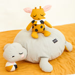 The Roommate Canvas Doll Goldy The Giraffe sitting on a turtle pouffe. 

