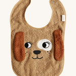 The Roommate Dog Baby Bib with an embroidered puppy face with floppy 3D ears. Cream background.