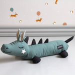 Roommate childrens mini dragon cushion on a white floor in front of some pink and grey wallpaper