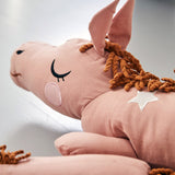 Close up of the Roommate childrens organic cotton lazy long horse cushion in the old rose colour on a grey background