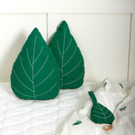 The Roommate Leaf Lullaby Music Mobile laying on a bed with two Roommate green Leaf cushions in the background