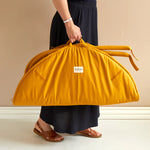 Adult carrying the Roommate Baby Gym in a Lion design by it's handle. The play gyn is folded in half