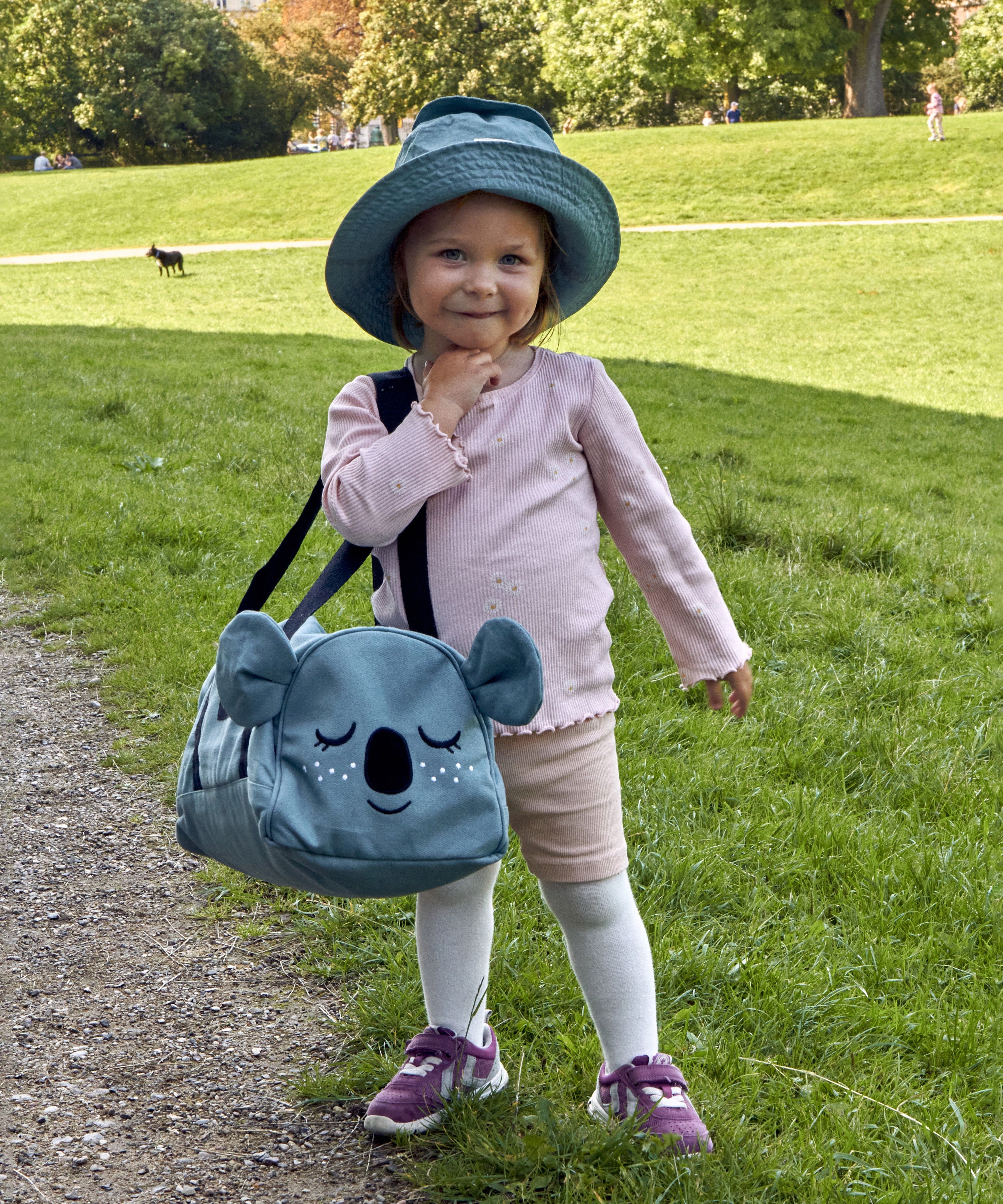 A child wearing the Roommate Koala bucket hat and carrying a koala bag.