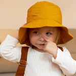 A child wearing the golden yellow Tiger bucket hat from Roommate. 