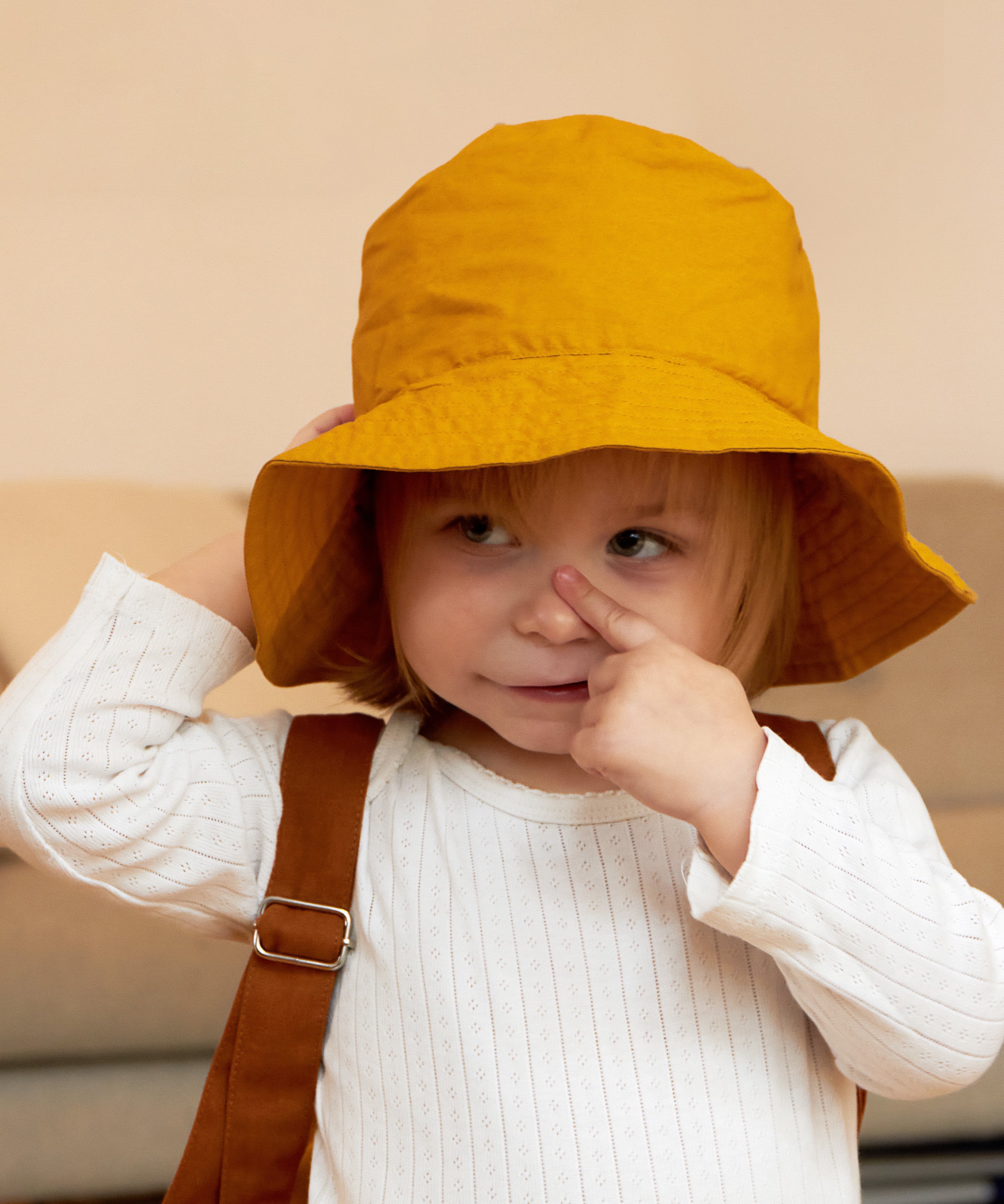 A child wearing the golden yellow Tiger bucket hat from Roommate. 