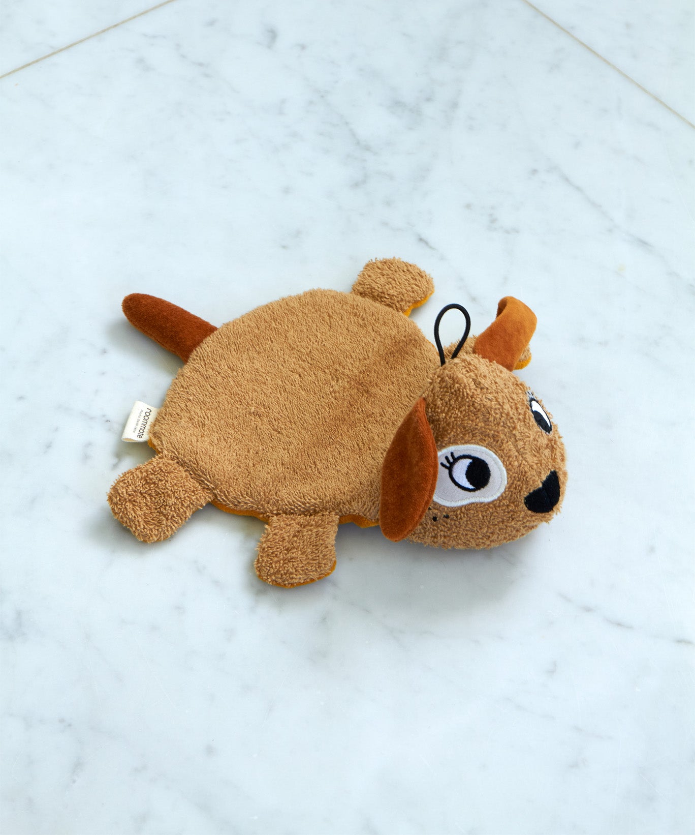 Roommate organic cotton dog washcloth bath toy shown alone on a light marble surface, highlighting the embroidered facial features, soft terry fabric, and hanging loop.