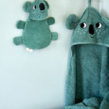 Roommate koala washcloth bath toy hanging on a wall hook next to a matching koala hooded towel, showing the built-in hanging loop used for drying after bath time.