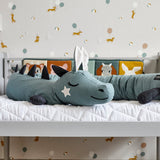 Roommate organic cotton long stuffed dragon cushion laying on a childs seat