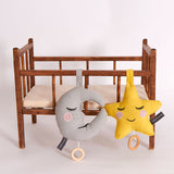 A star and moon Roommate Lullaby Music Mobiles hung on a little toy wooden bed.
