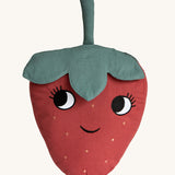 Roommate Organic Cotton Strawberry Cushion. A fun, soft Strawberry cushion with a red fruit body with big eyes and a smiling mouth, and green leafy top on a cream background