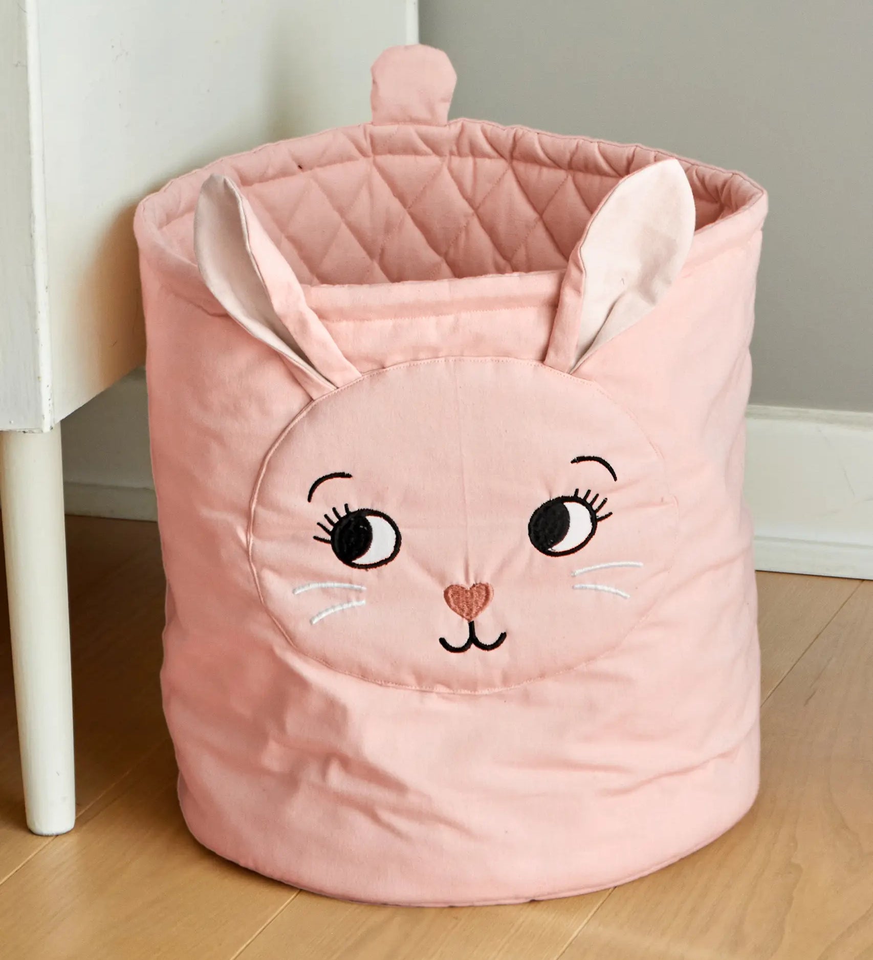 Roommate quilted basket with a pink bunny design placed on a wooden floor. 