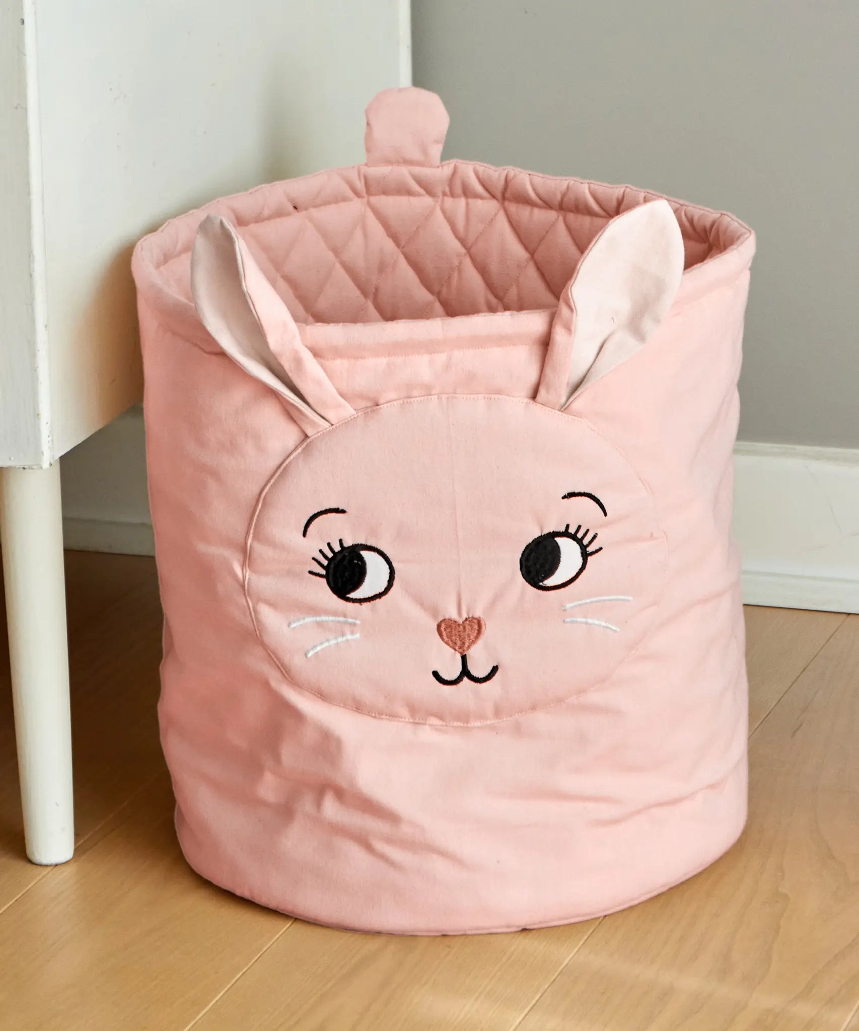 Roommate quilted basket with a pink bunny design placed on a wooden floor. 