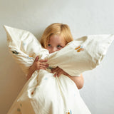 Child cuddling the Roommate single organic cotton duvet coverwith baby bugs print on a cream background. 