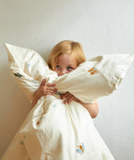 Child cuddling the Roommate single organic cotton duvet coverwith baby bugs print on a cream background. 