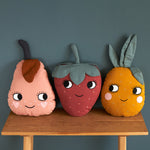 A child holding and cuddling the Roommate Organic Cotton Strawberry Cushion