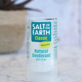 Salt Of The Earth classic unscented natural crystal deodorant stick standing on a marble surface with a plant in the background