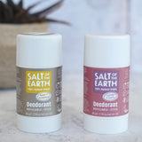 Lavender and amber Salt Of The Earth refillable deodorant sticks standing on a marble surface with a plant in the background