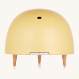 Maël Diffuser, a light yellow dome plug-in essential oil diffuser with wooden feet. 