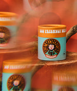 The Scrubber natural powder dry shampoo in 100% recycled cardboard packaging, in a ylang and rose scent on a psychedelic background.