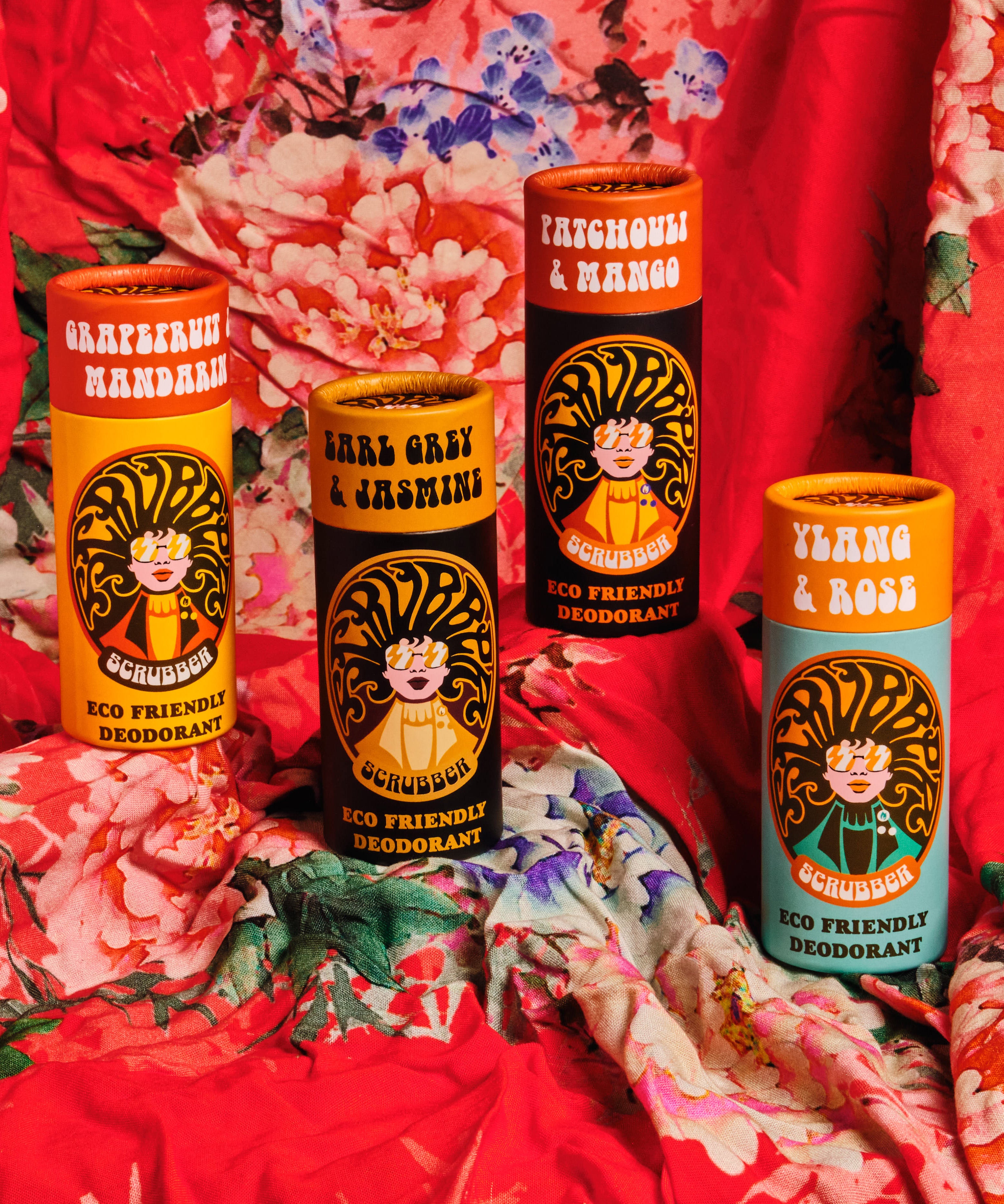 4 Scrubber plastic-free natural deodorant 
sticks with groovy packaging standing on a red floral cloth.