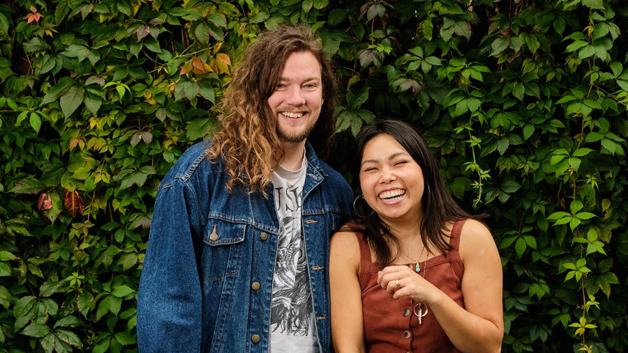 The founders of Scrubber; Siu-see and Scott, smiling in front of a leafy background.