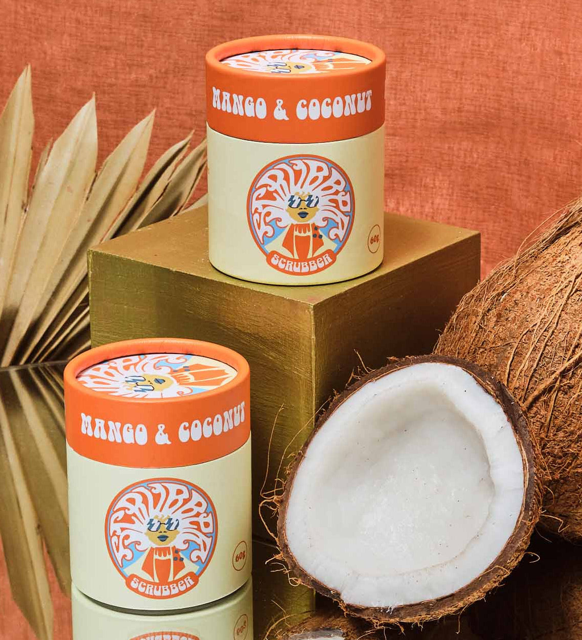 Two of the mango & coconut Scrubber natural powder dry shampoo in 100% recycled cardboard packaging in a retro display setup