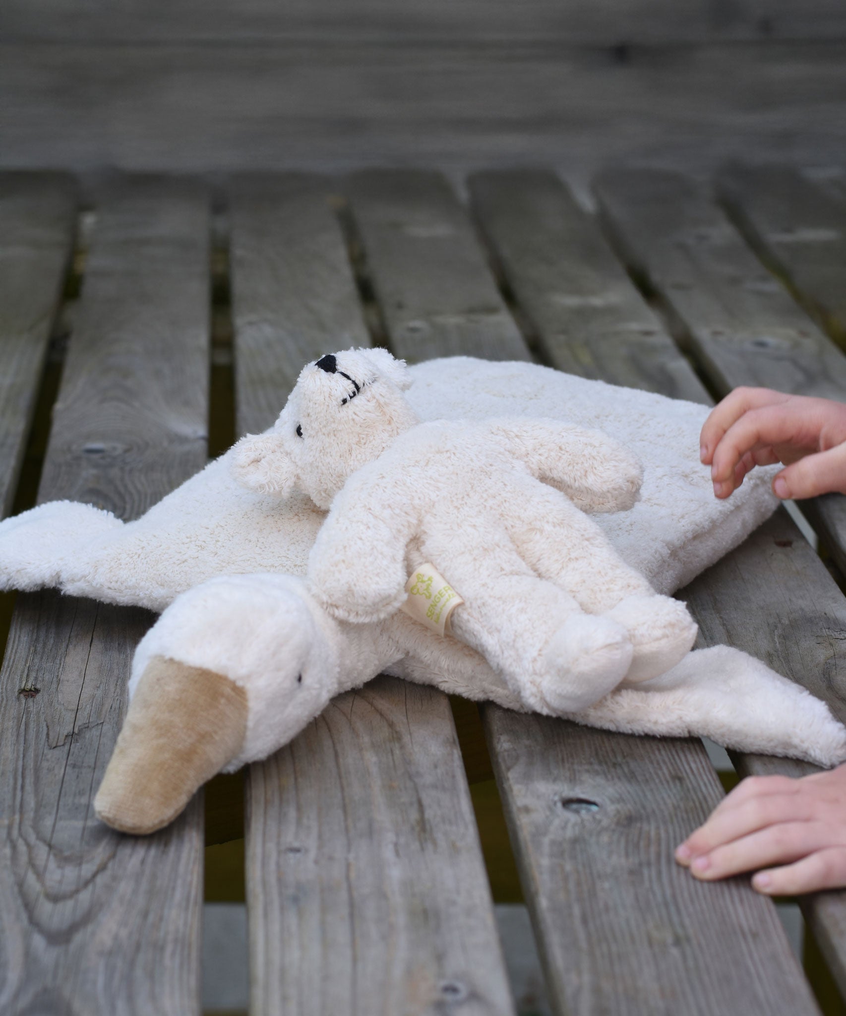 A Senger white baby bear placed on a A Senger goose pillow.