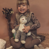 Child holding a GOTS organic cotton Senger baby grey and white cat soft toy. 