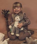 Child holding a GOTS organic cotton Senger baby grey and white cat soft toy. 