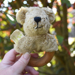 A Senger bear baby grasping toy being held up in an adult's hand.