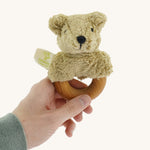 Senger Wooden Animal Grasping and Teething Toy - Bear held by a adult hand. A smooth cherry wood ring with a plush bear head made of 100% organic cotton stuffed with sheep wool.