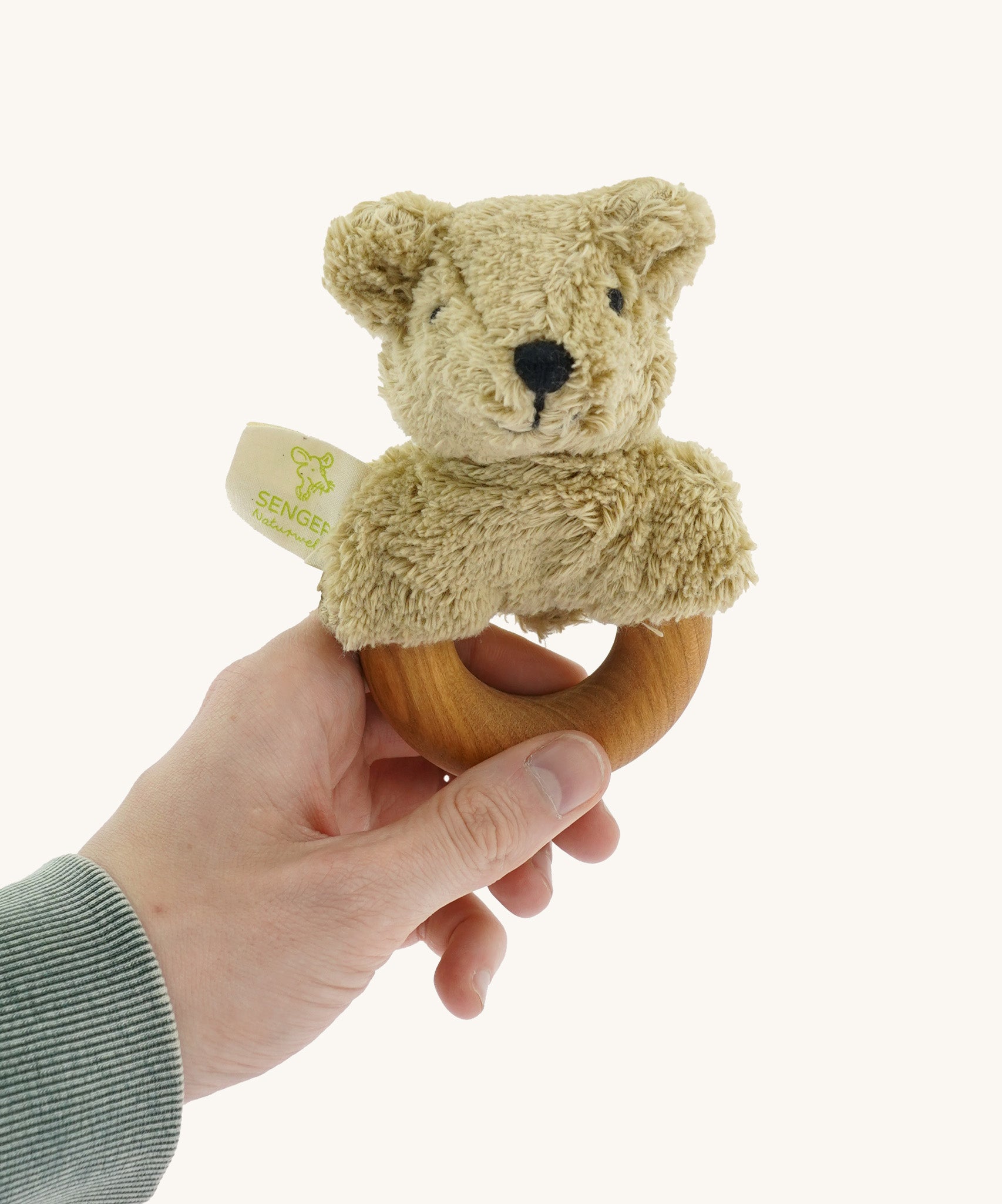 Senger Wooden Animal Grasping and Teething Toy - Bear held by a adult hand. A smooth cherry wood ring with a plush bear head made of 100% organic cotton stuffed with sheep wool.
