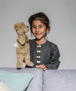 A child playing with a Senger beige bear Hand Puppet.