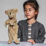 A child playing with the Senger beige bear Hand Puppet.