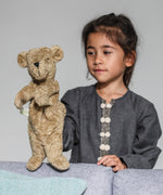 A child playing with the Senger beige bear Hand Puppet.