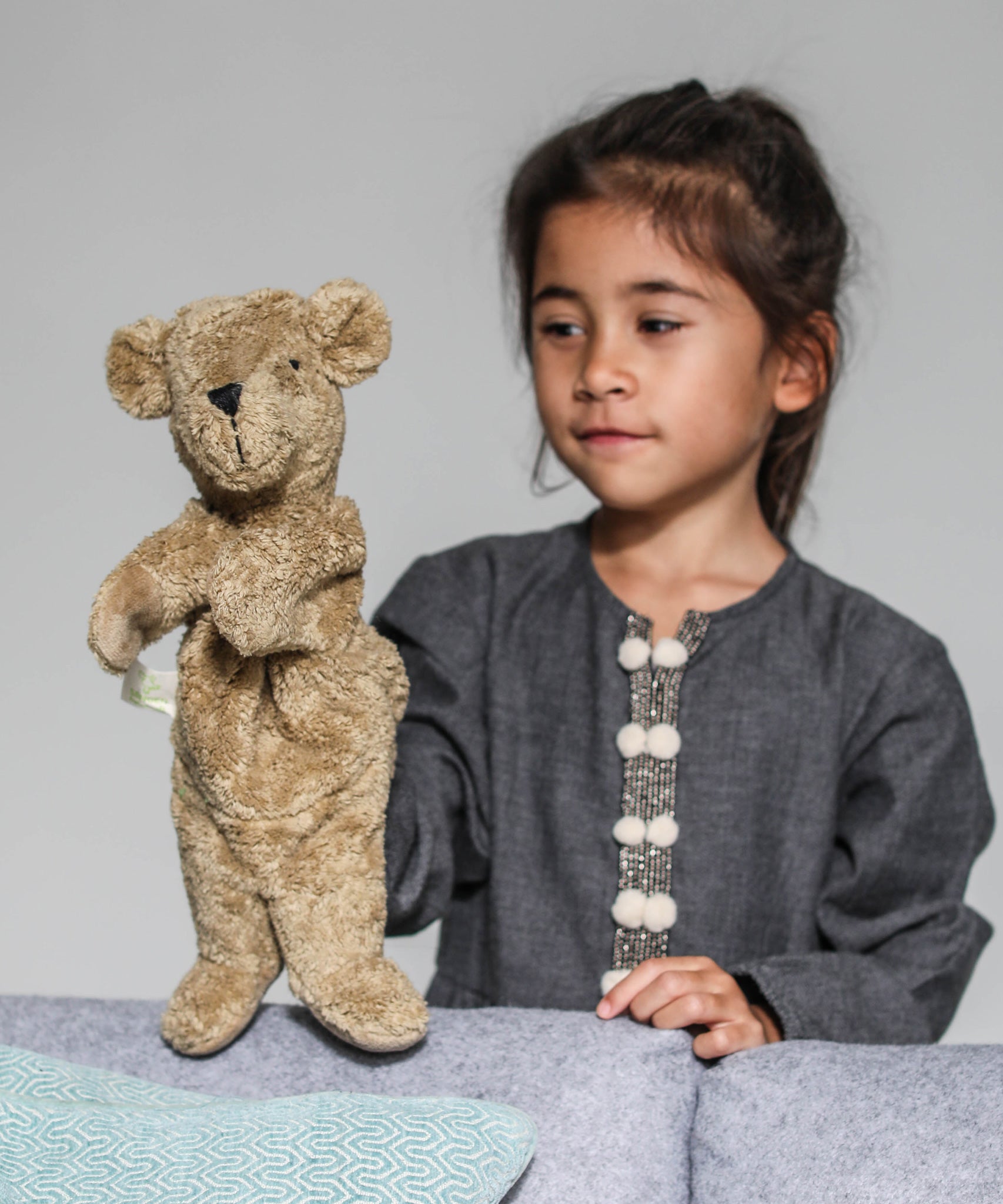 A child playing with the Senger beige bear Hand Puppet.