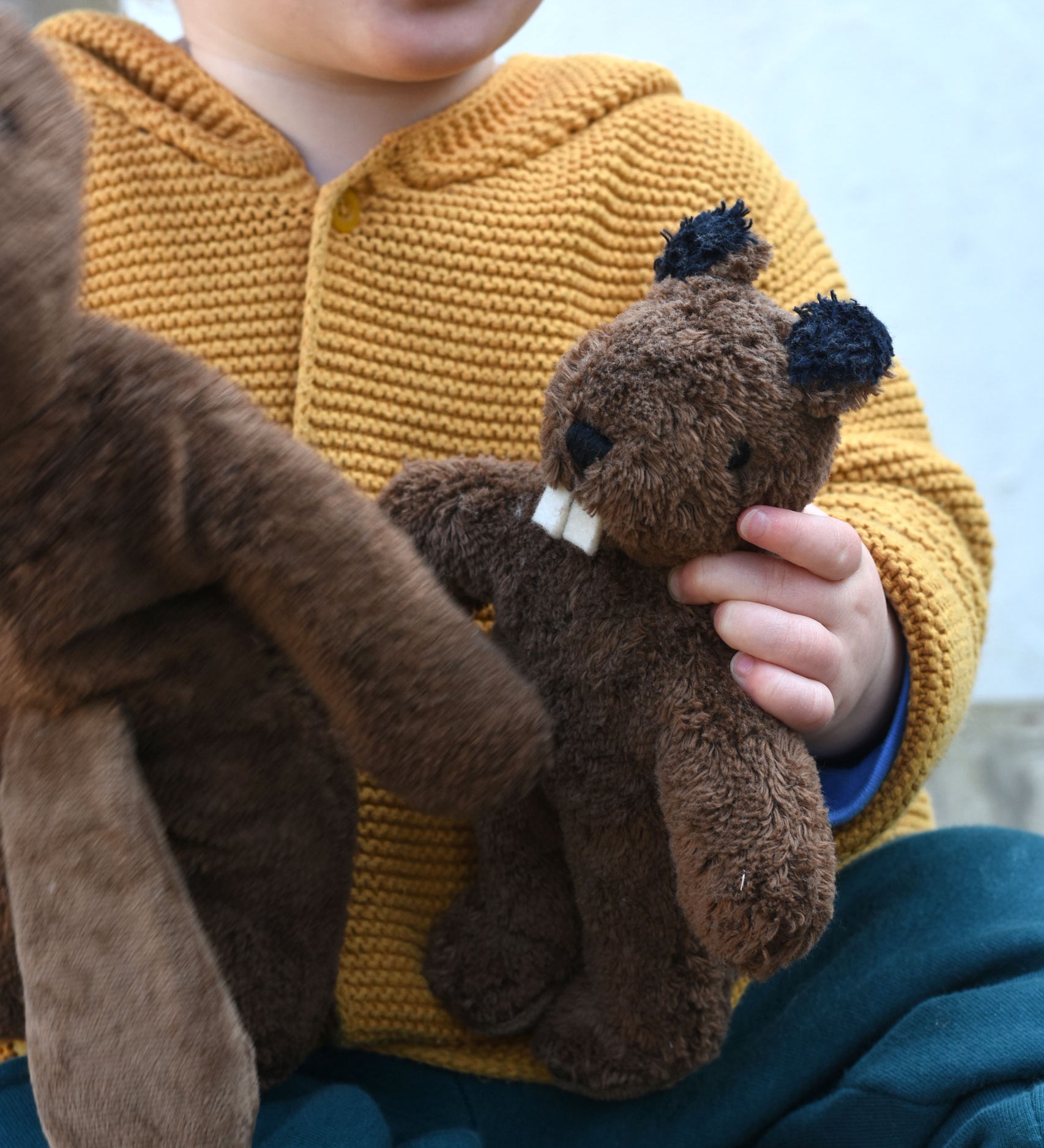 A close up of a Senger Baby Beaver Organic Soft Toy in a child's hands