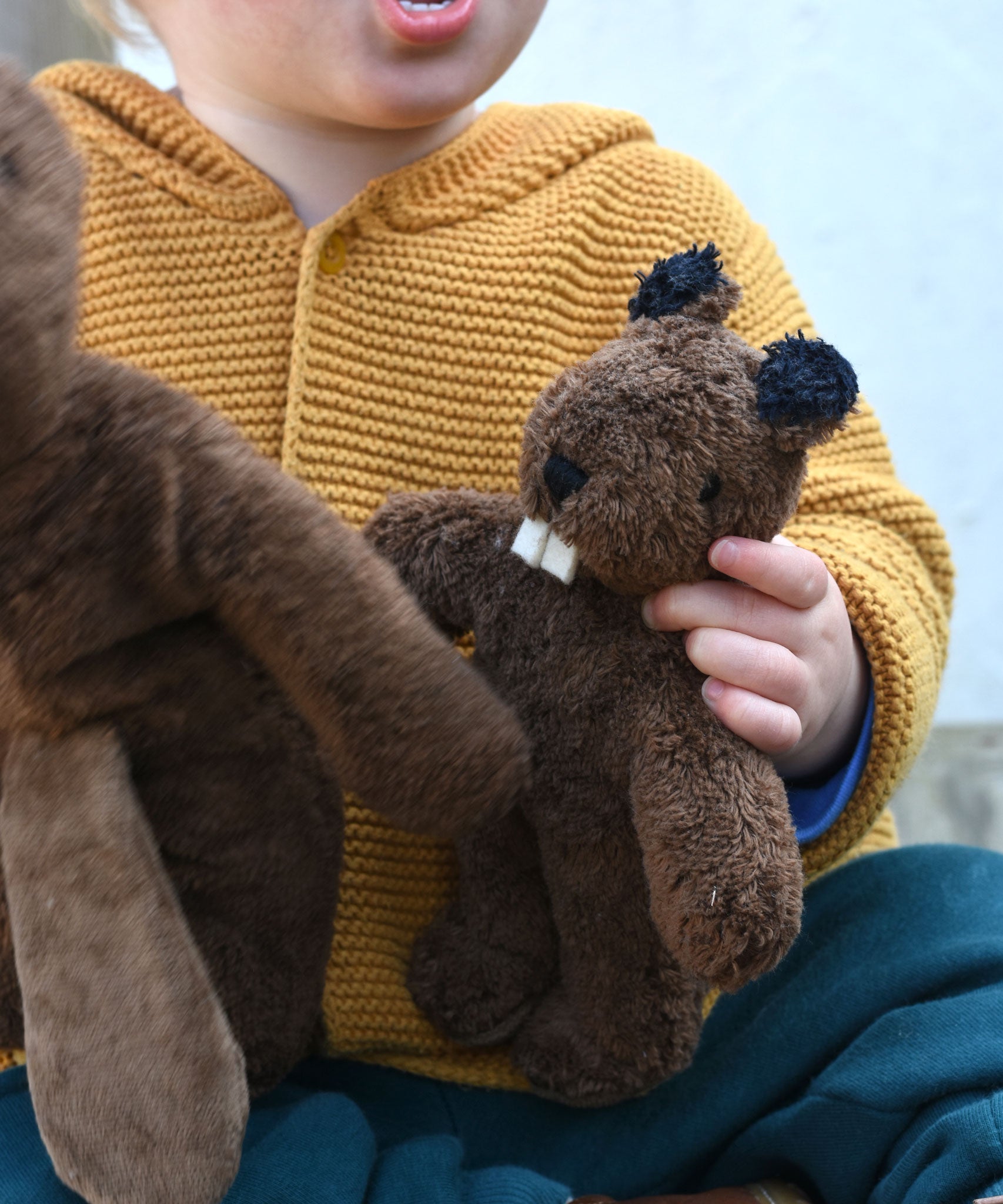A close up of a Senger Baby Beaver Organic Soft Toy in a child's hands