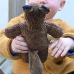 A close up of a Senger Baby Beaver Organic Soft Toy in a child's hands, the beaver is facing away from the camera and the tail can be seen.