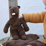 A child holdin up a Senger small floppy beaver toy by it's arm.