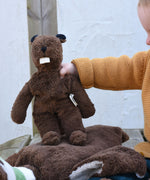 A child holdin up a Senger small floppy beaver toy by it's arm.