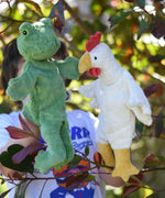 A child playing with the Senger frog and chicken puppets , one on each of their hands.