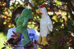 A child playing with the Senger frog and chicken puppets , one on each of their hands.