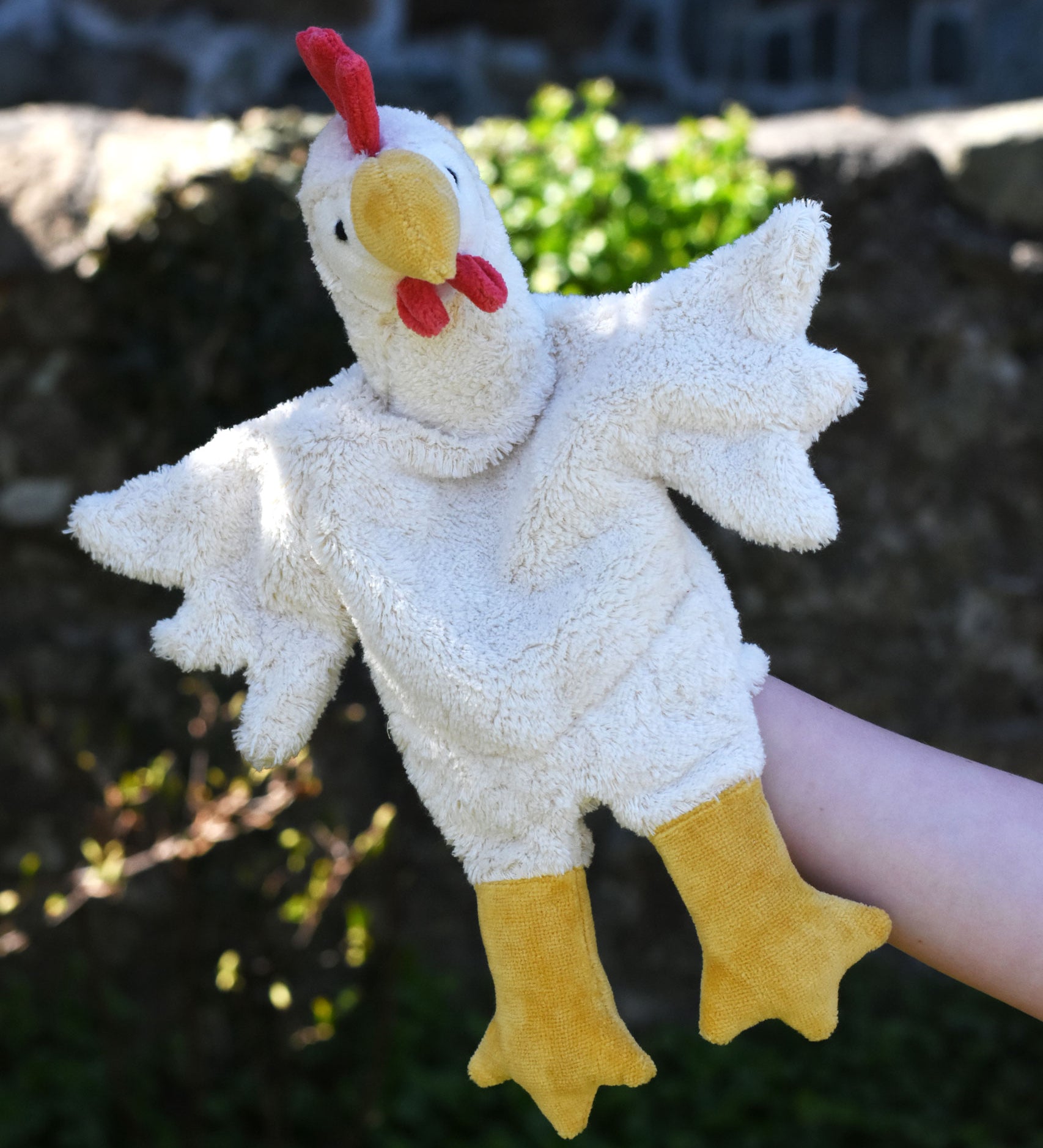 A close up of the Senger white chicken puppet in use on a child's hand.