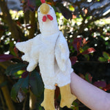 A close up of the Senger white chicken puppet in use on a child's hand.