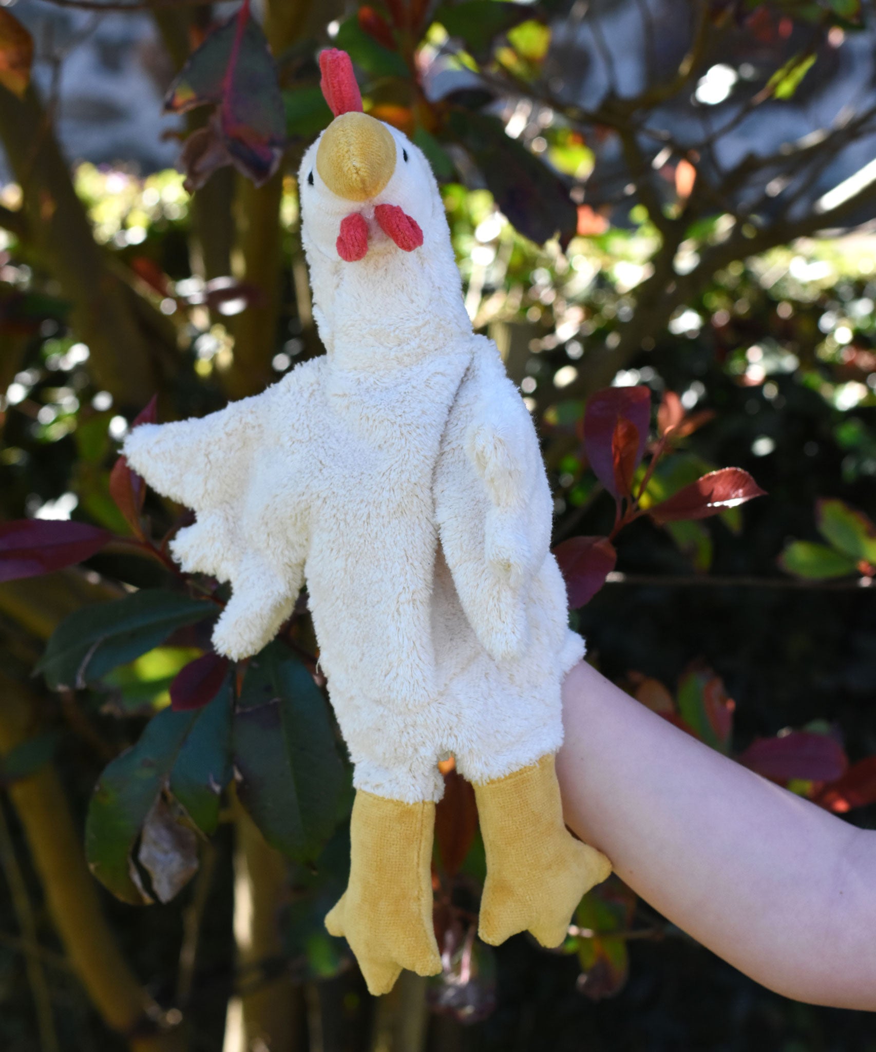 A close up of the Senger white chicken puppet in use on a child's hand.