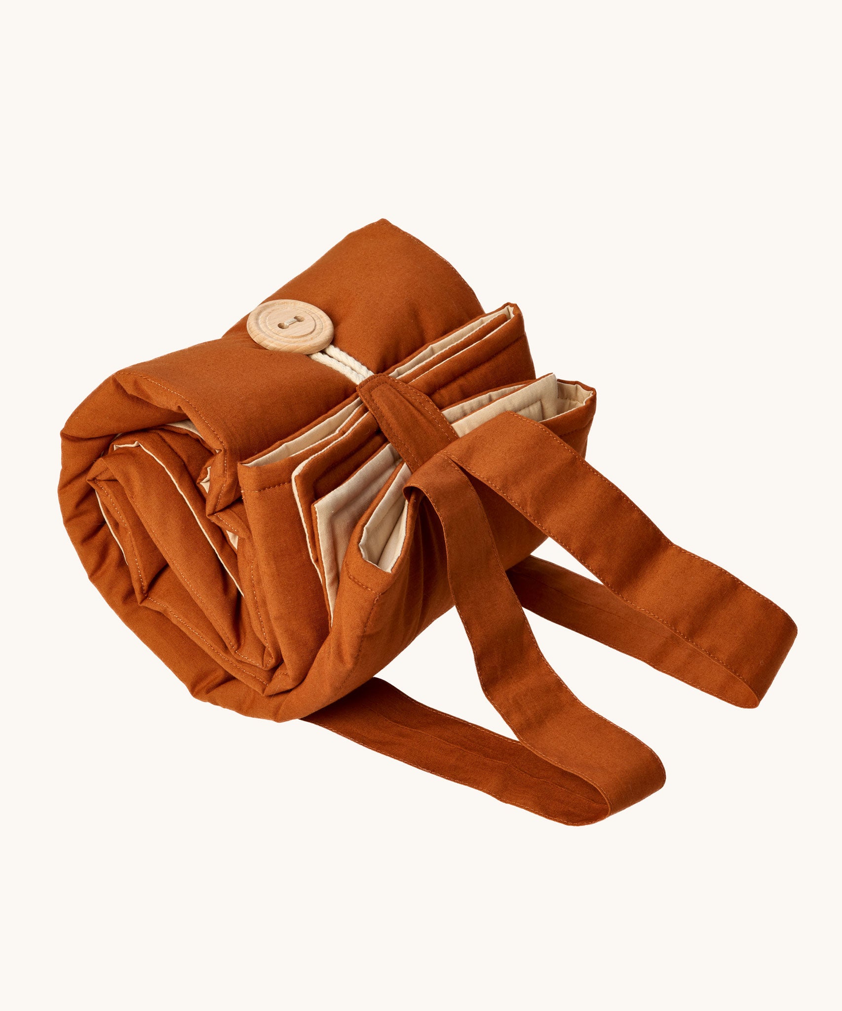 Senger cozy nap baby play mat. A padded blanket designed for babies to have a comfortable space whilst out and about. The mat is shown rolled up and secured with the button and loop. 