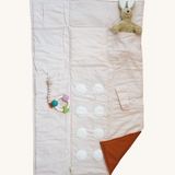The Senger Cozy Nap playmat, with a Senger cuddly rabbit and a natural rubber teether attached to demonstrate how you can use it.