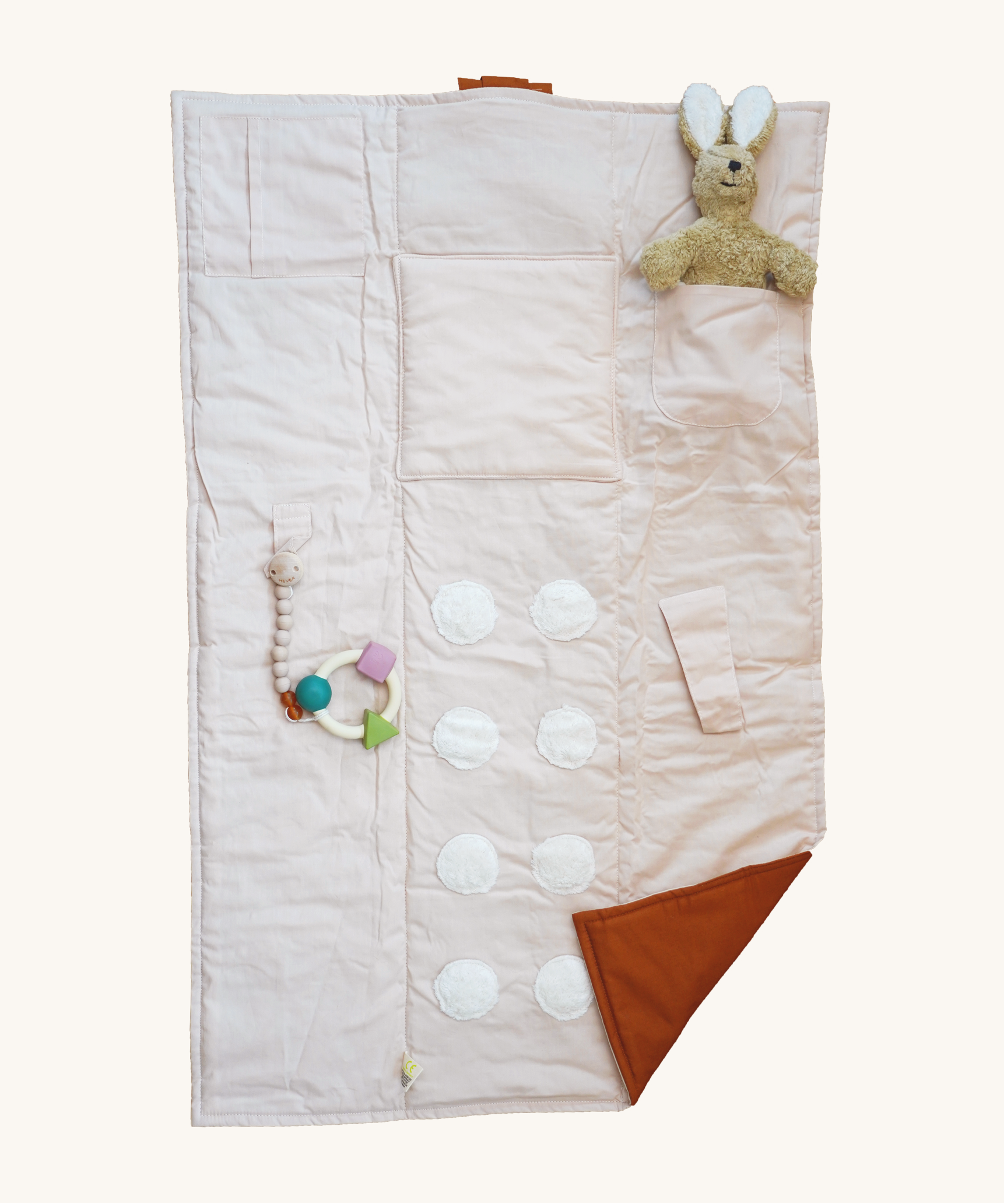 The Senger Cozy Nap playmat, with a Senger cuddly rabbit and a natural rubber teether attached to demonstrate how you can use it.