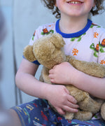 A close up of a small Senger beige cuddly teddy bear in a child's hands.